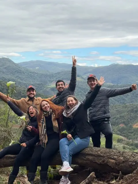 Mariana e amigos celebrando uma trilha com vista para as montanhas.