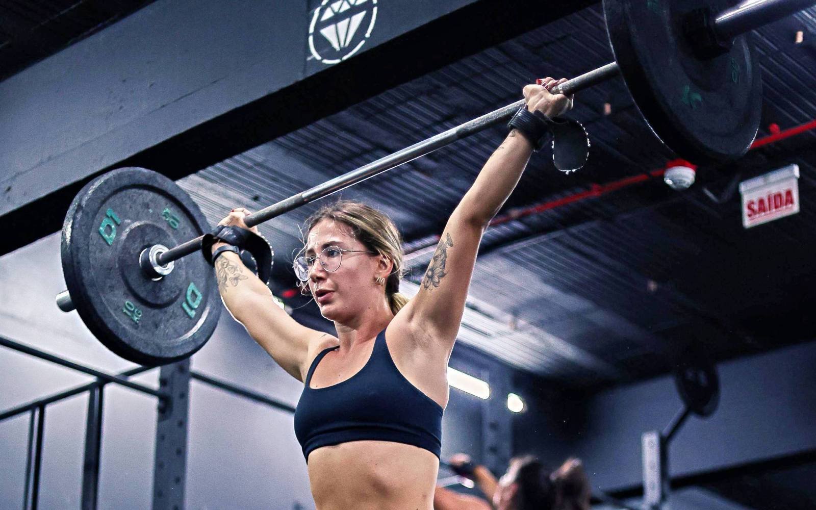 Mulher realizando levantamento de peso em um box de CrossFit